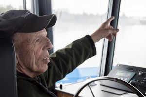Dave Schmelzer talks about past river adventures while co-piloting the Oscar B up the Columbia River on Friday morning. Schmelzer, a retired tugboat pilot, took turns guiding the ferry with the son of the real Oscar B, Gary Bergseng. Photo by Brooks Johnson
